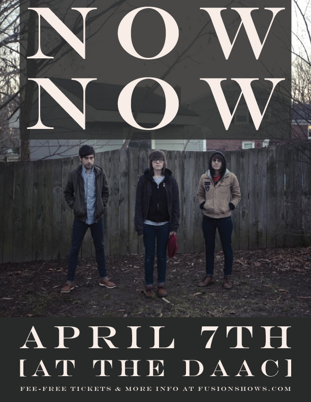 Three people wearing jackets standing in front of a wooden fence