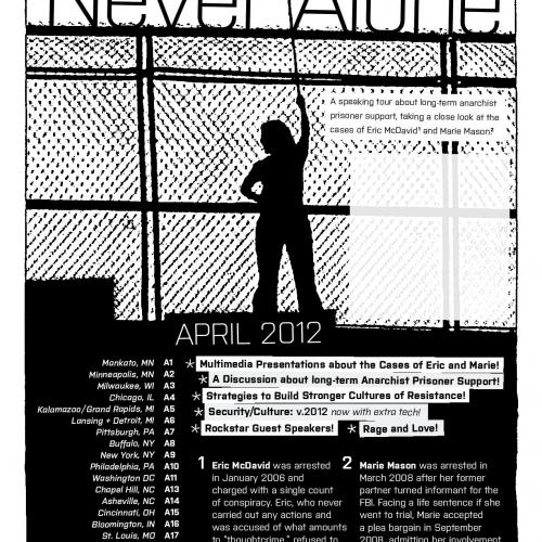 Silhouette of a figure holding a black flag aloft in front of a security fence